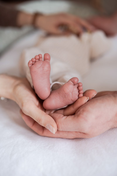 Startseite Mutter und Vater halten sorgsam die Füßchen ihres neugeborenen Babys